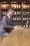 Smiling businessman working on laptop, wine shelf in the background