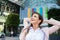 Smiling businesswoman with hands on head against modern building