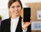 Smiling businesswoman in office hold cellphone in hands and show