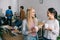 smiling businesswomen with coffee mugs and businessmen standing behind