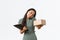 Smiling busy successful female asian store owner, answering phone call, holding package ready for delivery and clipboard