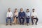 Smiling candidates job seekers sitting in row with resumes in hand and waiting for interview invitation turn