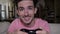 Smiling captivated teenager with game controller having fun playing video game sitting on couch at home in slow motion -