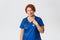 Smiling caring middle-aged redhead doctor, female physician in blue scrubs with stethoscope smiling at camera, treating