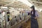 Smiling caring young female dairy farm worker stroking a cow and holding a digital tablet.