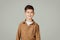 Smiling caucasian 6 years old little boy pupil in casual looks at empty space isolated at gray studio background