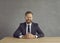 Smiling caucasian businessman sitting at desk and looking at camera studio shot