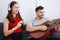 Smiling Caucasian Couple love happy together in living room. handsome husband playing a guitar and lovely wife listening to music