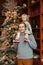 Smiling Caucasian father holding baby girl on shoulders by decorated Christmas tree. Happy family celebrating Christmas or New