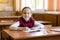 Smiling caucasian girl sitting at desk in class room and ready to study. Portrait of young pre schoolgirl. Happy pupil