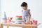 Smiling Caucasian little kid girl in cute dress, surprised on birthday party, looking at beautiful rainbow cake decorated with