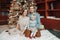 Smiling Caucasian mother and father with baby girl sitting together by decorated Christmas tree. Happy family celebrating