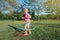smiling Caucasian preschool blonde girl playing with hoola hoop in park outside on summer day