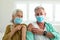 Smiling caucasian senior couple with plaster on arm after vaccination, wearing face masks