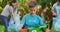 Smiling caucasian son outdoors holding recycling crate, collecting plastic waste with parents