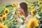 Smiling Caucasian woman with blond hair smelling sunflower in farm on sunny day