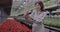 Smiling Caucasian woman enjoying smell of red flower in greenhouse. Portrait of positive mid-adult biologist admiring