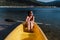 Smiling caucasian woman holding oar sitting on yellow canoe in lake during sunny day. summer time. Sports, adventure and nature