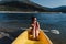 Smiling caucasian woman in swim wear holding oar sitting on yellow canoe in lake during sunny day. summer time. Sports, adventure