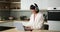 Smiling Caucasian Woman Working with Laptop in the Kitchen