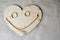 A smiling, cheerful face made of a wooden heart, wedding gold rings and a female gold chain