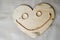 A smiling, cheerful, kind face made of a wooden heart for Valentine`s Day, wedding gold rings and a female gold chain