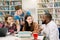 Smiling cheerful modern multiracial students sitting in the library and reading books during their preparation for exams