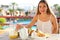 Smiling cheerful woman eating breakfast in her vacation resort hotel view from outside private balcony