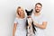 Smiling cheerful young man and woman in white T-shirts holding their pet