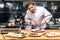 smiling chef cutting fried meat with knife