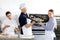 Smiling Chef Passing Baking Sheet To Colleague In