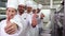 Smiling chefs standing in a row giving thumbs up