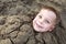 Smiling child buried in sand on beach