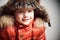 Smiling child in fur hood and orange winter jacket.fashion boy