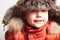 Smiling child in fur hood and orange winter jacket.fashion boy