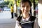 Smiling child girl with backpack on her back,holding a books on her arms going to school,cheerful schoolgirl wearing a school