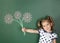 Smiling child girl hold drawn flowers near school blackboard