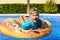 Smiling child looking at camera on a round float in a swimming pool