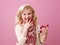 Smiling child on pink background eating raspberries on fingers