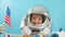 A smiling child waves his hand, looks at the camera, close-up,Pilot flies into space.Child plays at home in an astronaut