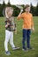 Smiling children holding badminton racquets while standing on green grass