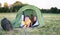 Smiling children lying in the tent in the park. Camping, tourism and teenagers activity or leisure concept