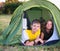 Smiling children lying in the tent in the park. Camping, tourism and teenagers activity or leisure concept