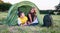 Smiling children lying in the tent in the park. Camping, tourism and teenagers activity or leisure concept