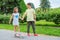 Smiling children playing in the park. Brother, teaches sister to ride a skateboard