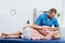 smiling chiropractor massaging back of patient that lying on massage table