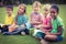 Smiling classmates sitting in grass and holding books