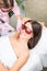 Smiling client cosmetology clinic having Armpit laser hair removal. Beautiful smiling woman client in red glasses having