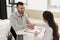 smiling client shaking hands with doctor in office with laptop and insurance