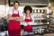 Smiling colleagues in red apron with arms crossed